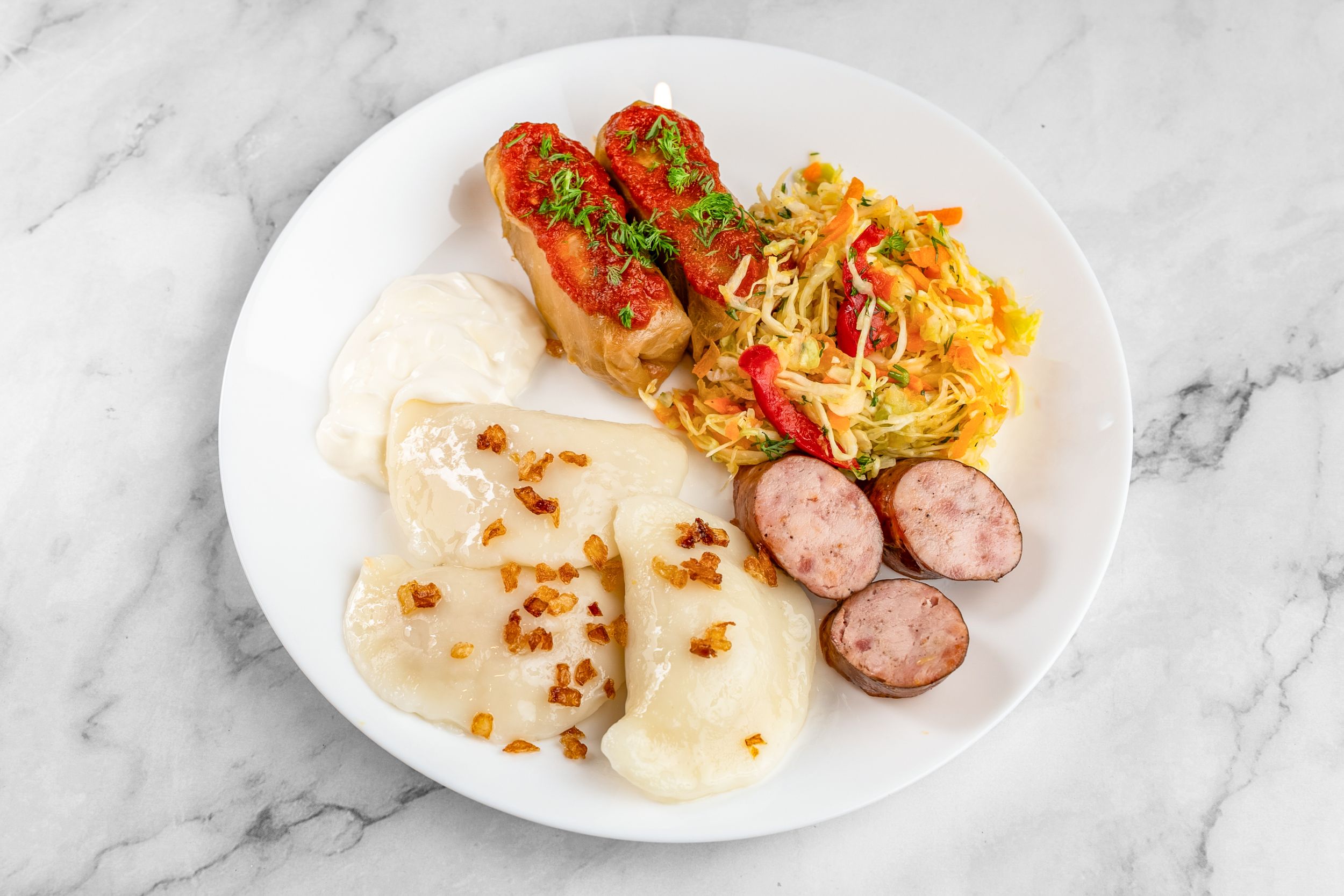 A plate of DONYA perogies with sausage and sour cream